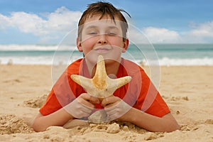 Boy on beach holding a sea star