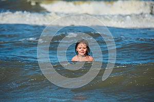 Boy at beach during summer vacation. Kid swimming in sea with wawes. photo