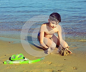 Boy on the beach take sun bathing play with sand