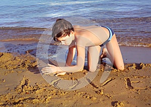 Boy on the beach take sun bathing play with sand