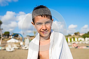 Boy on the beach in a white towel for swimming