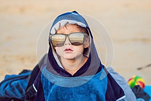 The boy on the beach wrapped in a towel, wet after swimming