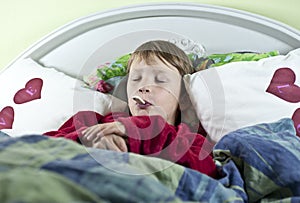 Boy in bed with thermometer