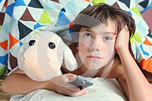 Boy in bed watch tv with remote control