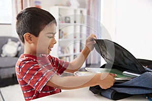 Boy In Bedroom Packing Bag Ready For School photo
