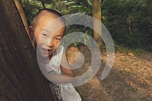 Boy hiding behind tree