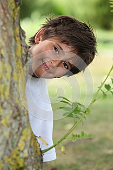 Boy behind tree trunk