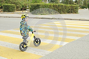 A boy with a bicycle crosses a pedestrian crossing with yellow markings