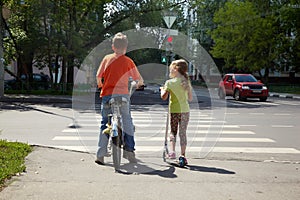 Boy with bicycle and his sister with scooter stand