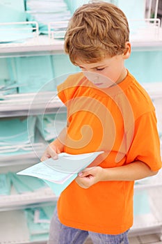 Boy in big shop chooses school notebook