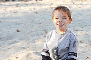 Boy with a big smile in sand