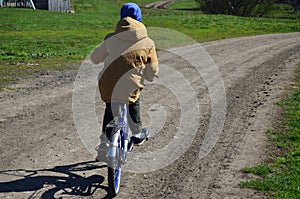 Boy on a bike rides on a rural dirt road spring rest on quarantine