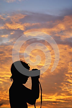 Boy with binoculars at sunset photo