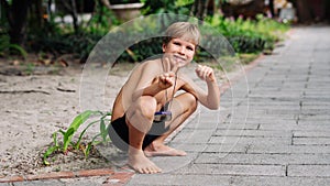 Boy blond freckles squatting sit smiling show gesture thumbs up shirtless bare chested shorts nature