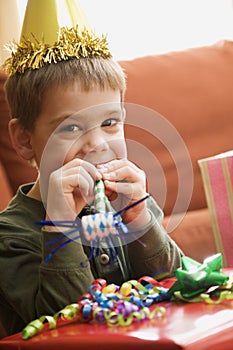 Boy blowing noisemaker.