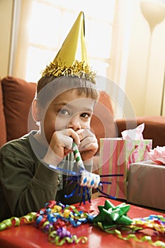 Boy blowing noisemaker.