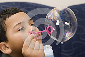 Boy blowing soap bubble.