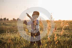 Boy blowing soap bubbles while an excited kid enjoys the bubbles. Happy kid in a meadow