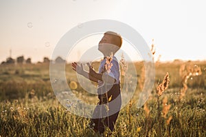 Boy blowing soap bubbles while an excited kid enjoys the bubbles. Happy kid in a meadow