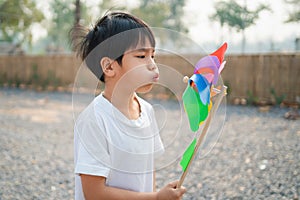 boy blowing a toy windmill in the morning