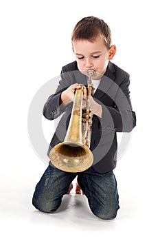 Boy blowing into a trumpet against white background