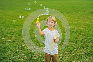 A boy blows bubbles against the grass