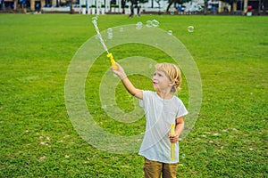 A boy blows bubbles against the grass