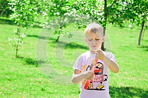 The boy blows bubbles in the park.