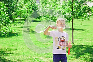 The boy blows bubbles in the park.