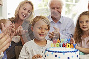 Chico sopla afuera pastel de cumpleanos velas sobre el familia fiesta 