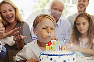 Boy Blows Out Birthday Cake Candles At Family Party