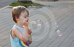 The boy blows soap bubbles.