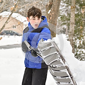 Boy With Blue and Black Snowsuit Shoveling
