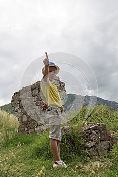 boy in a blue hat staing near ruins of the ancient fortress of S