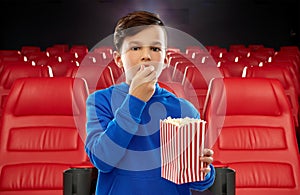 Boy in blue hoodie eating popcorn at movie theater