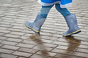 Boy in blue rubber boots walk otdoor in the rainy day photo