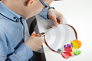 Boy in a blue shirt with mum. The boy`s mom cuts scissors with a plastic work done by a child.