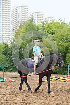Boy in blue shirt riding a horse in park near the