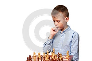A Boy in a blue shirt on a white background plays chess and and thinks what move to make