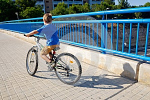 Boy in blue t-shirt learning to ride a bike on a summer day