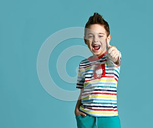 Boy in blue yellow stripes tshirt show thumbs up sign positive smiling yelling on light mint background