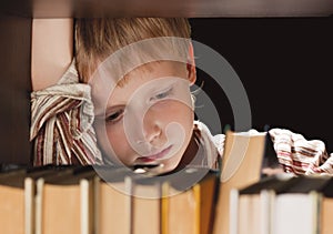 The boy at a bookcase gets the book.