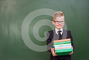 Boy with books standing near chalkboard