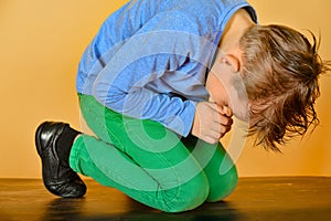 The boy bowed in prayer before God. The child is kneeling in the prayer of repentance before the Supreme Creator