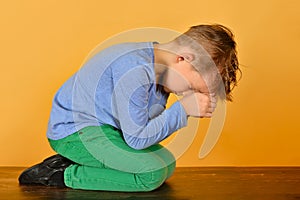 The boy bowed in prayer before God. The child is kneeling in the prayer of repentance before the Supreme Creator