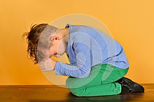 The boy bowed in prayer before God. The child is kneeling in the prayer of repentance before the Supreme Creator photo