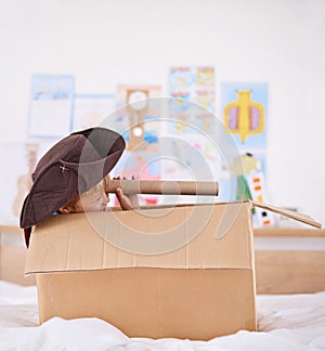 Boy, box and pirate hat with spyglasses on bed for playing, adventure and game as creativity. Kid, cardboard and home