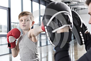 Boy boxer practicing punches with coach