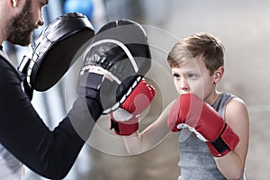 Boy boxer practicing punches with coach