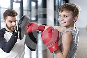 Boy boxer practicing punches with coach